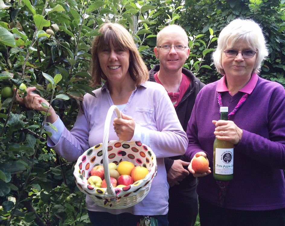 Volunteers picking this year's apples, and showing off a bottle of last year's juice